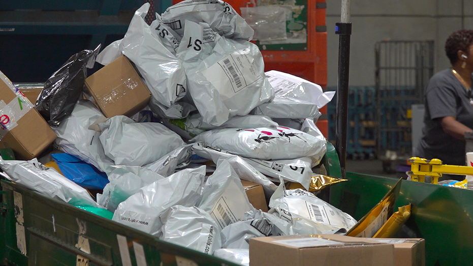 A large pile of about 50 packages being dumped on a conveyor belt