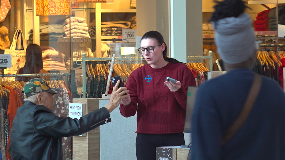 A man in a wheelchair shows something on his phone to a lady.